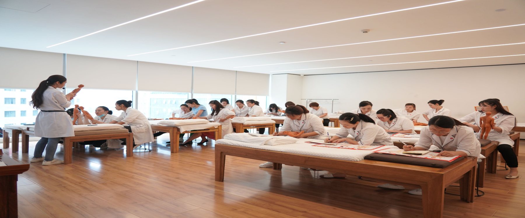 常乐推拿师培训现场，学员在按摩床旁集体实操